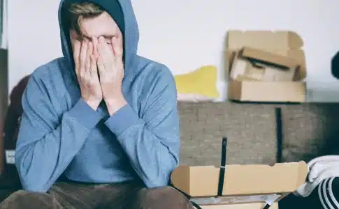 man covering face with both hands while sitting on bench