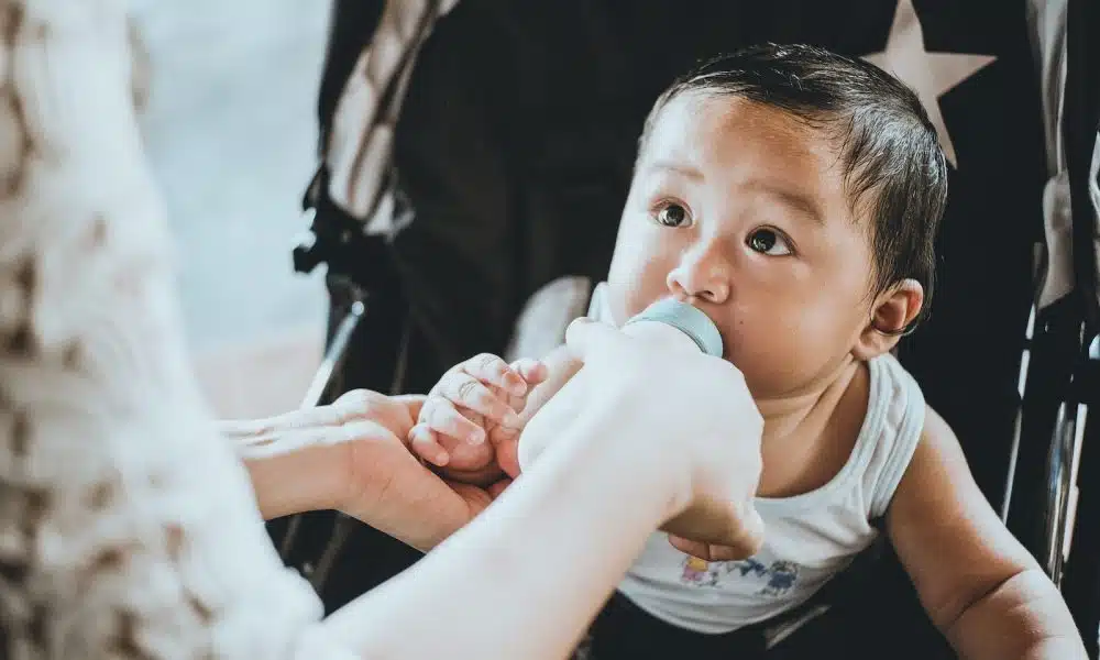 person feeding baby from feeding bottle