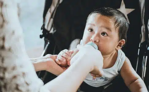 person feeding baby from feeding bottle